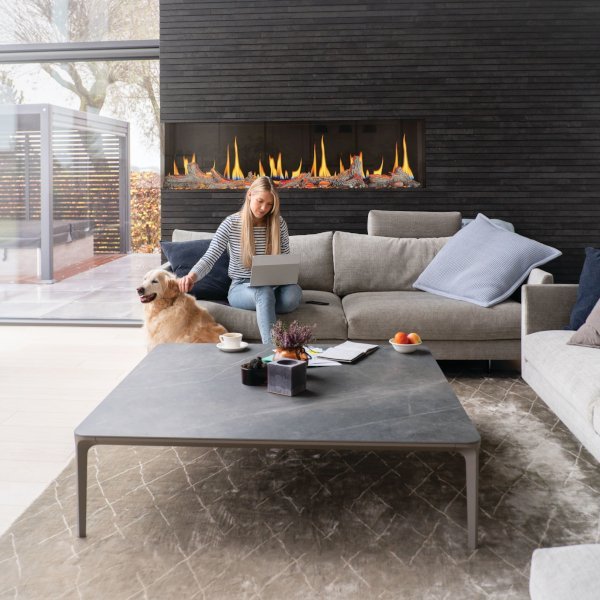 Woman petting her dog in her massive living room with a linear fireplace
